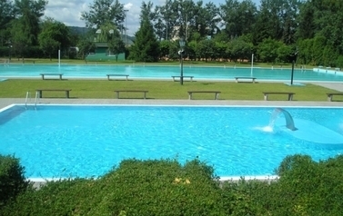 Otwarty basen w Czarnkowie - obiekt pusty, widać błękit wody i fragment zielonych trawiastych fragment&oacute;w między dwoma zbiornikami mniejszym i z tyłu większym.