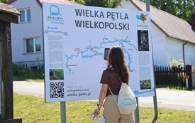 turystka przy tablicy informacyjnej.